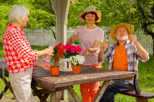 Retired man and two women taking care of flowers sitting together