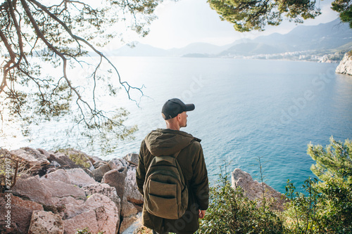 Tourist with a backpack near the sea. Travel alone. Looks into the distance.