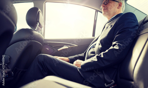 transport, business trip, safety and people concept - senior businessman driving on car back seat © Syda Productions