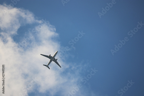 Airplane flying in blue sky on background of white clouds. Silhouette of a commercial plane, turbulence concept