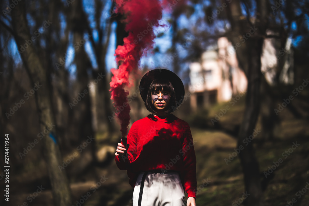 Beautiful woman in red smoke grenade standing in the street Beautiful woman in red smoke grenade standing in the street