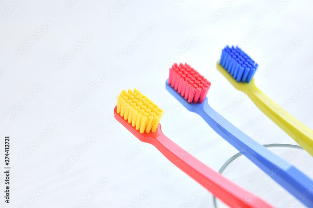 Three colorful plastic toothbrush with soft focus on blurred neutral background. Multicolored toothbrushes for personal daily healthcare. Toothbrushes for daily oral hygiene and caries protection Three colorful plastic toothbrush with soft focus on blurred neutral background. Multicolored toothbrushes for personal daily healthcare. Toothbrushes for daily oral hygiene and caries protection