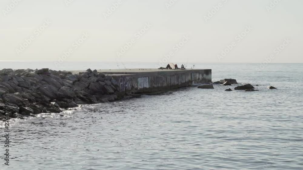 Horizontal panoramic view of a sea and concrete dock. Fishing rods and ocean waves. Summer in Barcelona Horizontal panoramic view of a sea and concrete dock. Fishing rods and ocean waves. Summer in Barcelona