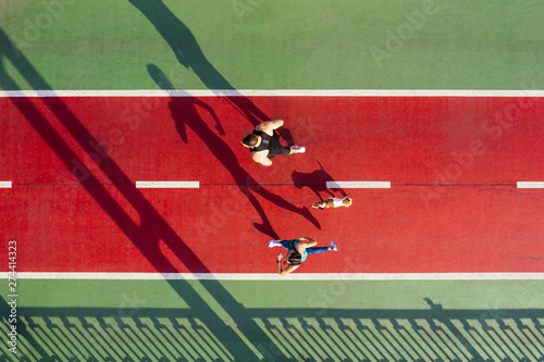 Sport theme. Runners with dog on green and red. Summer morning active couple. Aerial drone top view photo