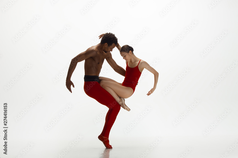 Graceful classic ballet dancers dancing isolated on white studio background. Couple in bright red clothes like a combination of wine and milk. The grace, artist, movement, action and motion concept.