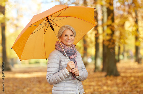 old age, weather and season concept - portrait of happy senior woman with umbrella at autumn park