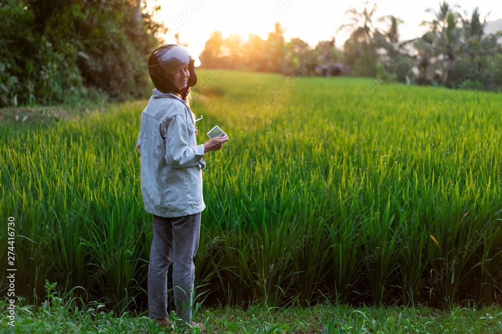girl traveling on a motorbike, stopped to take a photo of a rice field at sunset.