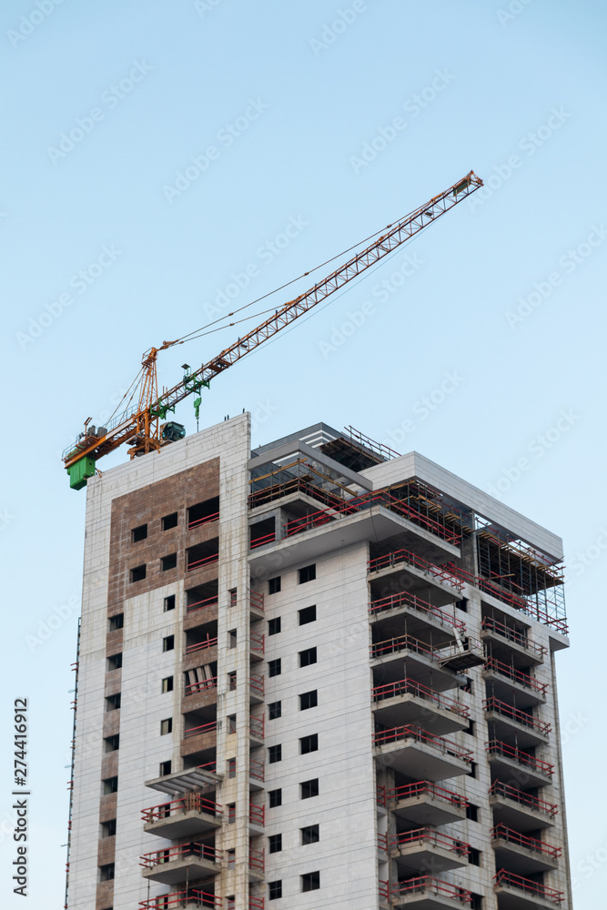 Construction crane building a house against a blue sky Construction crane building a house against a blue sky