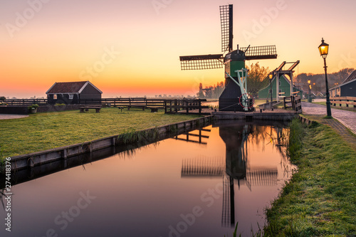 Holländische Windmühle bei Sonnenaufgang am Wasser