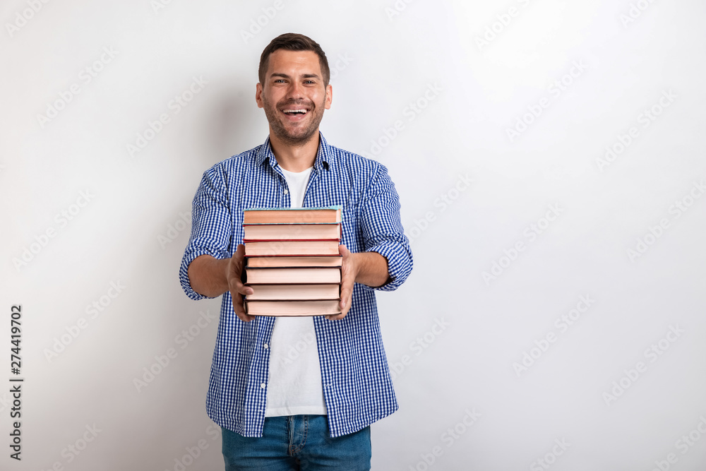 Portrait of happy young man holding books in his straight hands. Back to school Portrait of happy young man holding books in his straight hands. Back to school