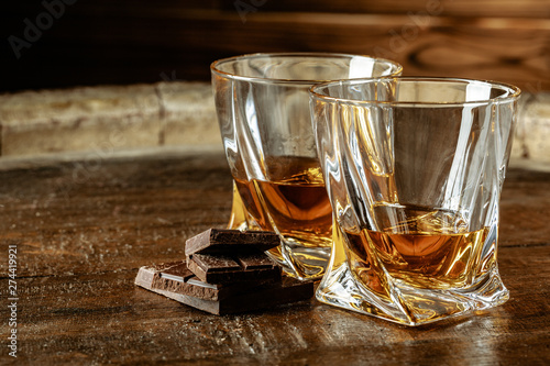 Two glasses of bourbon or scotch, or brandy and pieces of dark chocolate