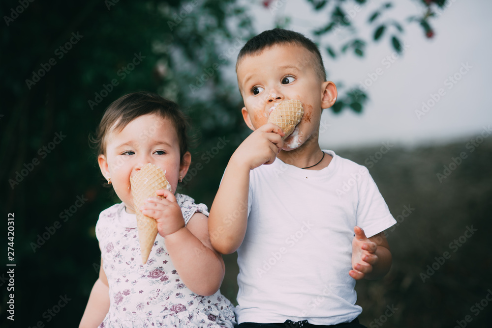 Cute kids Brother and sister are very cute outside in summer eating ice cream in the horn Cute kids Brother and sister are very cute outside in summer eating ice cream in the horn