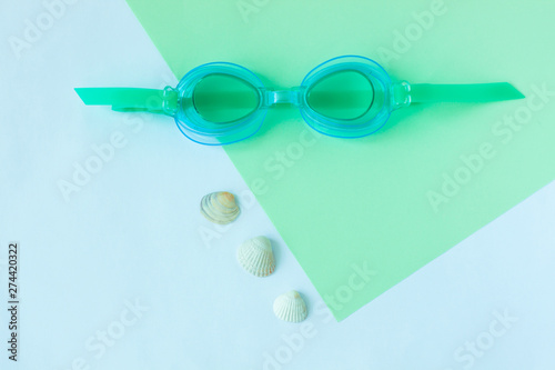 Summer flatlay with watersport goggles  mint and light blue background  minimalistic style  copy space.