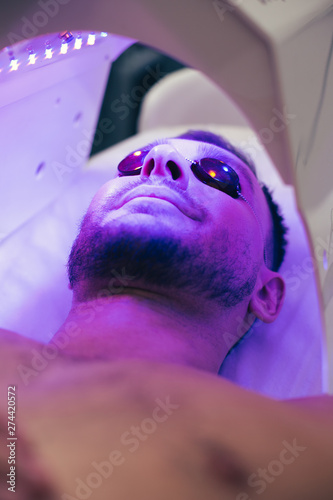Bild auf Leinwand Calm man resting in solarium in beauty salon