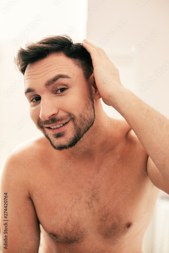 Cheerful man touching his hair and looking glad Cheerful man touching his hair and looking glad