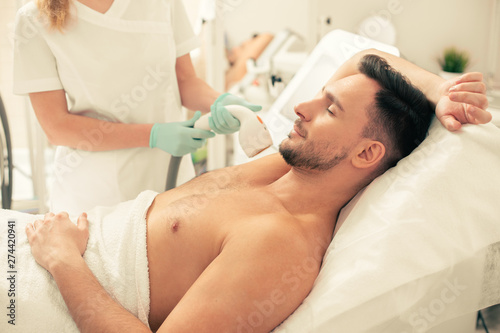 Man removing underarm hair and smiling with closed eyes