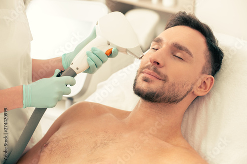 Calm man during the procedure of laser hair removal on his face
