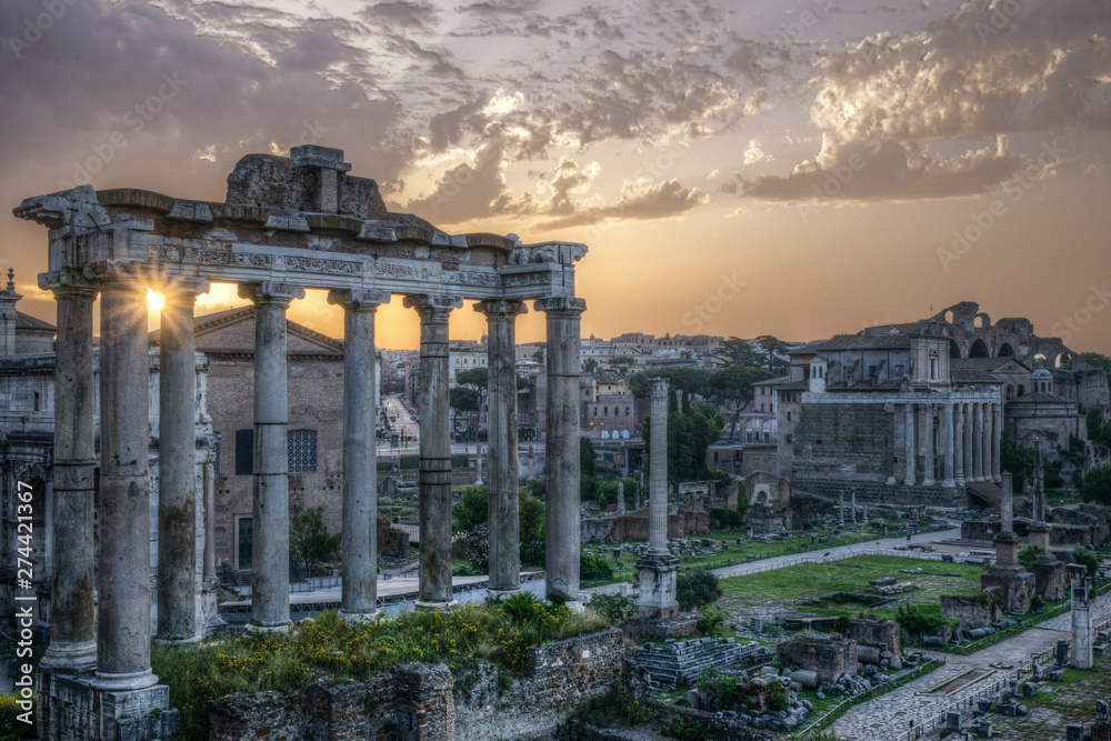 Rome. View of the Imperial Forums with the sun rising between the ancient columns.