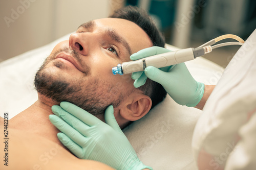Young man looking calm during the painless skin procedure photo