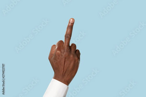 Fotografi Male hand in white shirt demonstrating a gesture of fuck isolated on blue studio background