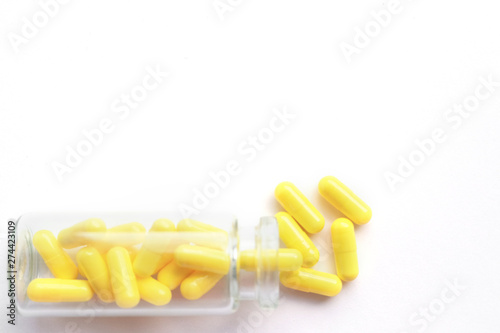 Yellow capsules from glass bottle on white background. copyspace for text. Epidemic, painkillers, healthcare, treatment pills and drug abuse concept