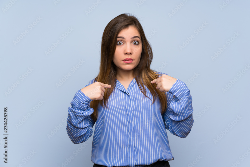 Fototapeta premium Young girl over isolated blue wall with surprise facial expression