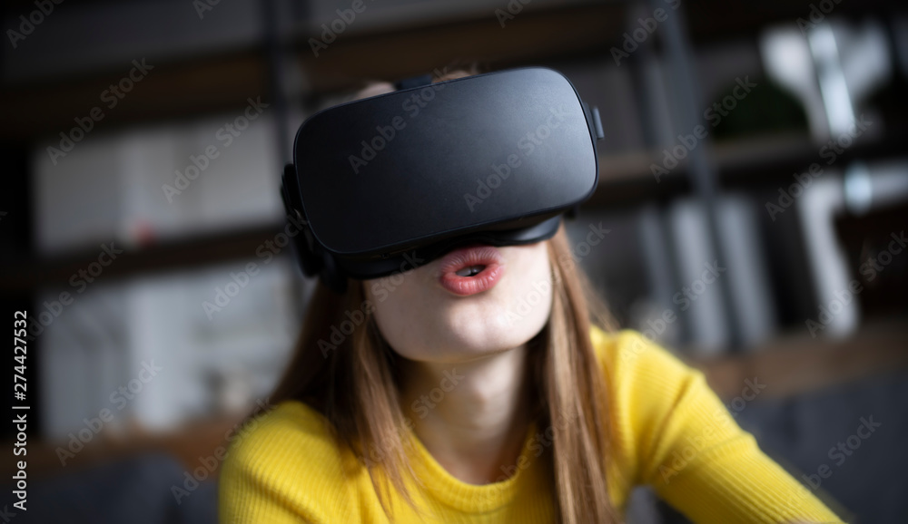 Cute girl plays the game on the console. Happy young woman using a virtual reality headset Cute girl plays the game on the console. Happy young woman using a virtual reality headset