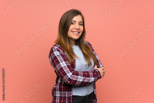 Young girl over pink wall with arms crossed and looking forward