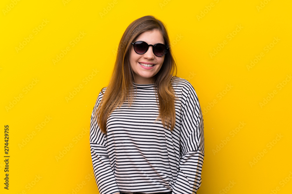 Young girl over yellow wall with glasses and happy Young girl over yellow wall with glasses and happy