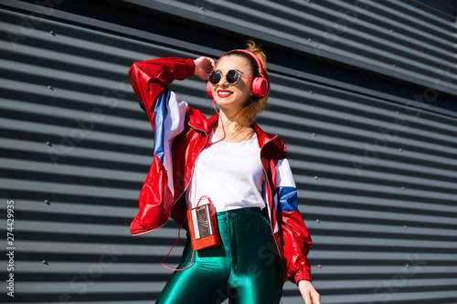 Back in time 90s 80s. Stylish girl in retro jacket and vintage cassette player listens to music, fashion trends, entertainment, heat in summer