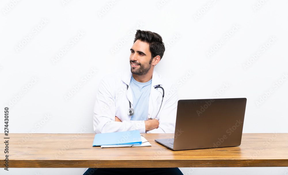 Young doctor man with his laptop over isolated wall looking to the side Young doctor man with his laptop over isolated wall looking to the side