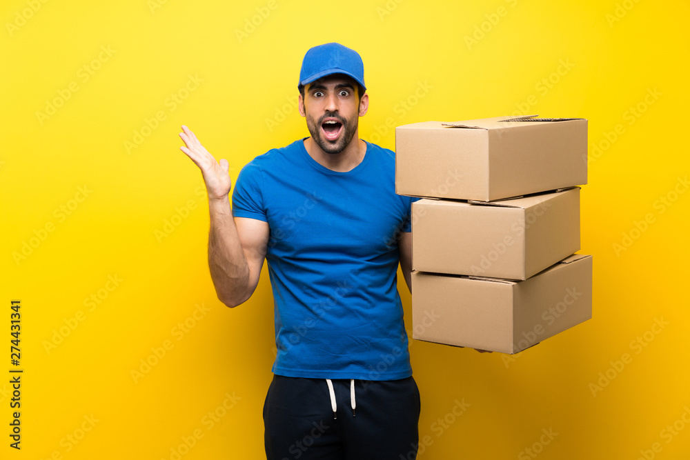 Young delivery man over isolated yellow wall with shocked facial expression Young delivery man over isolated yellow wall with shocked facial expression