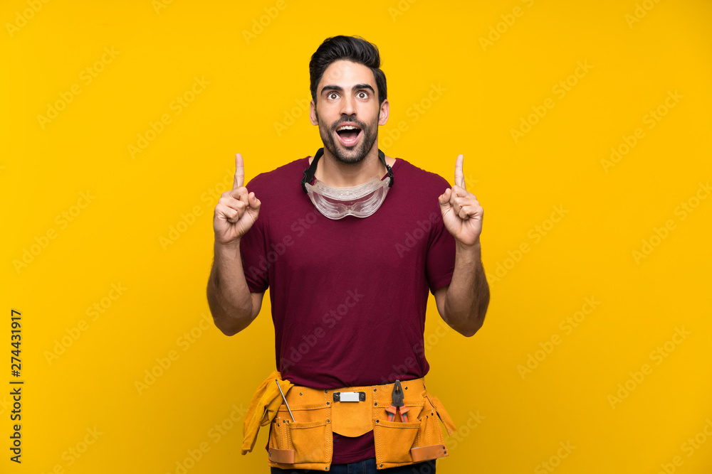Handsome young craftsman over isolated yellow background pointing up a great idea Handsome young craftsman over isolated yellow background pointing up a great idea