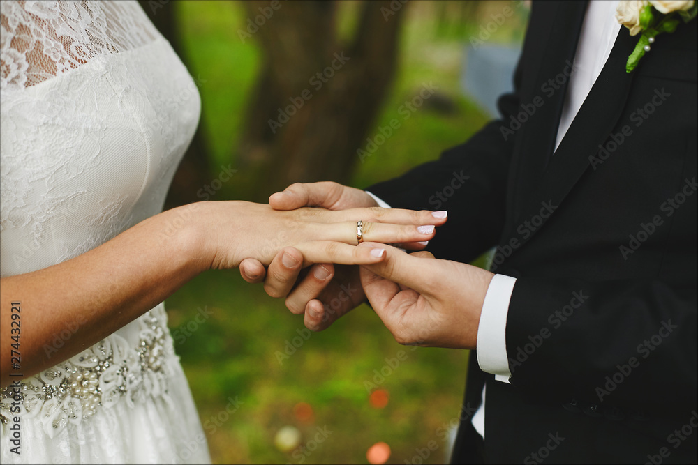 Stylish groom puts on the engagement ring on the finger of his ...