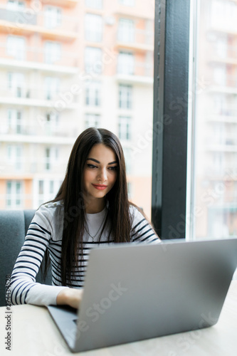 Beautiful smiling Caucasian woman blogger dressed smart casual sitting in cafeteria and using laptop. Free Download Beautiful smiling Caucasian woman blogger dressed smart casual sitting in cafeteria and using laptop. - GFXLoad