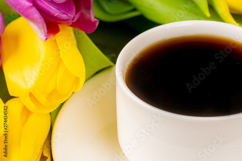 Yellow and purple tulips and coffee cup. Close up shot.