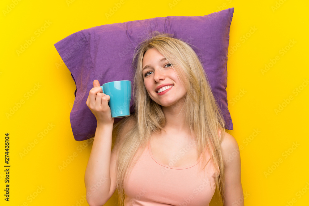 Young blonde woman in pajamas and holding a cup of coffee Young blonde woman in pajamas and holding a cup of coffee