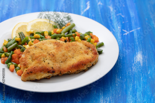 fried chicken with boiled vegetables and lemon on white dish