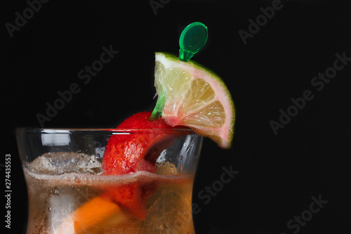 the top of a bright cocktail with a slice of orange and lime, a lot of color on a black background
