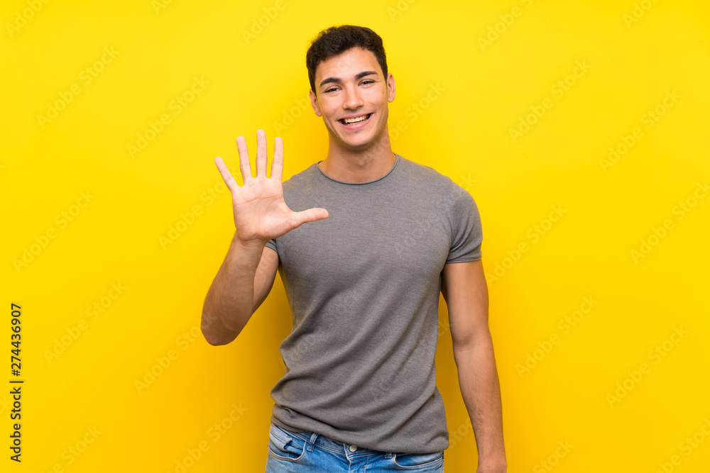 Handsome man over isolated yellow wall counting five with fingers Handsome man over isolated yellow wall counting five with fingers