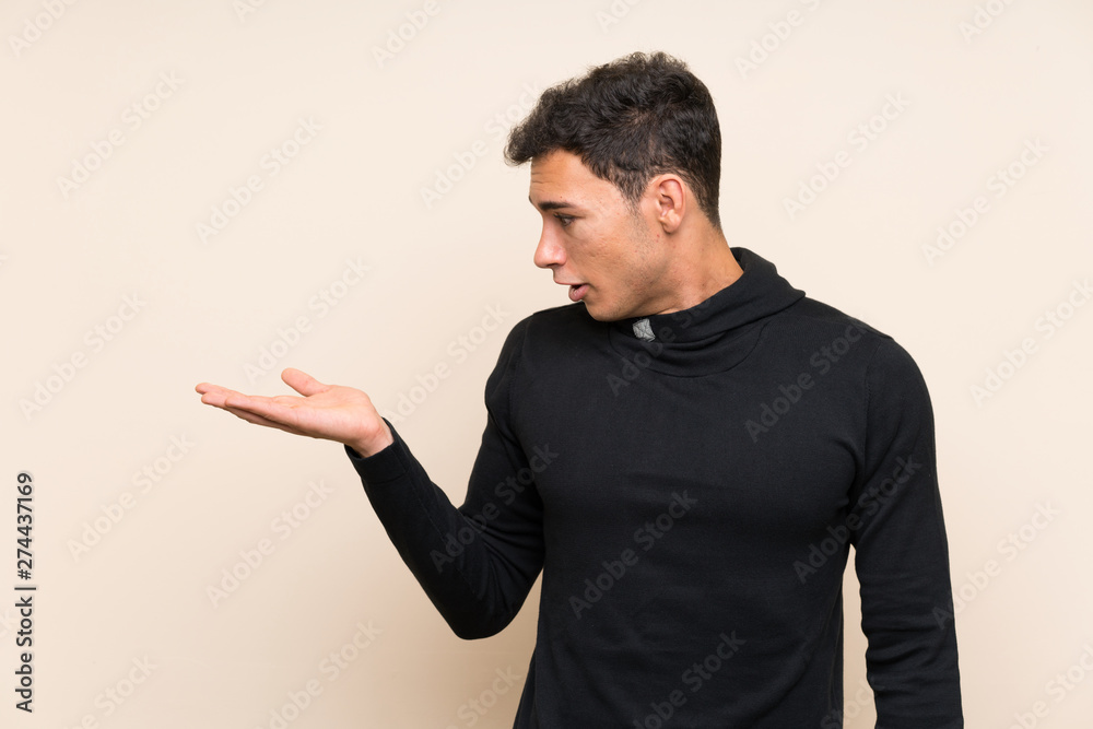 Handsome man over isolated background holding copyspace imaginary on the palm Handsome man over isolated background holding copyspace imaginary on the palm