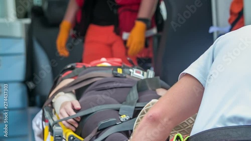Slowly putting an injured person on stretchers into an ambulance.