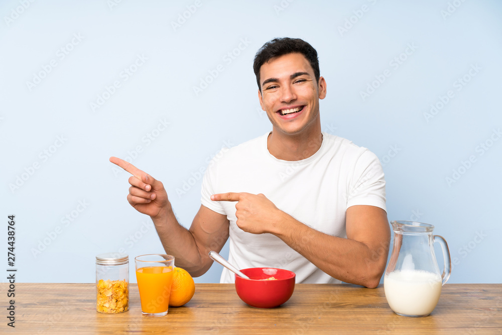 Handsome man in having breakfast pointing finger to the side