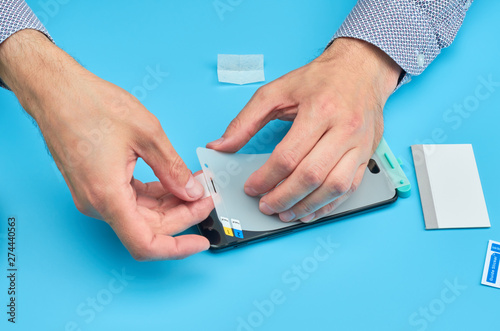 The man replacing the broken tempered glass screen protector for smartphone.