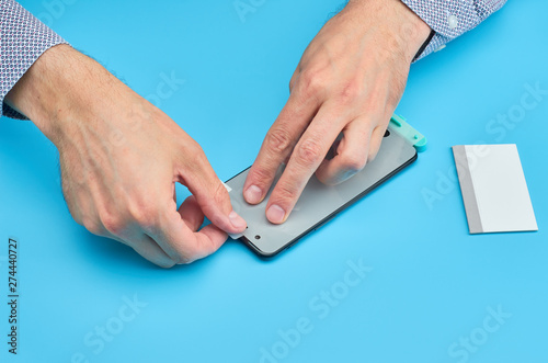 The man replacing the broken tempered glass screen protector for smartphone.