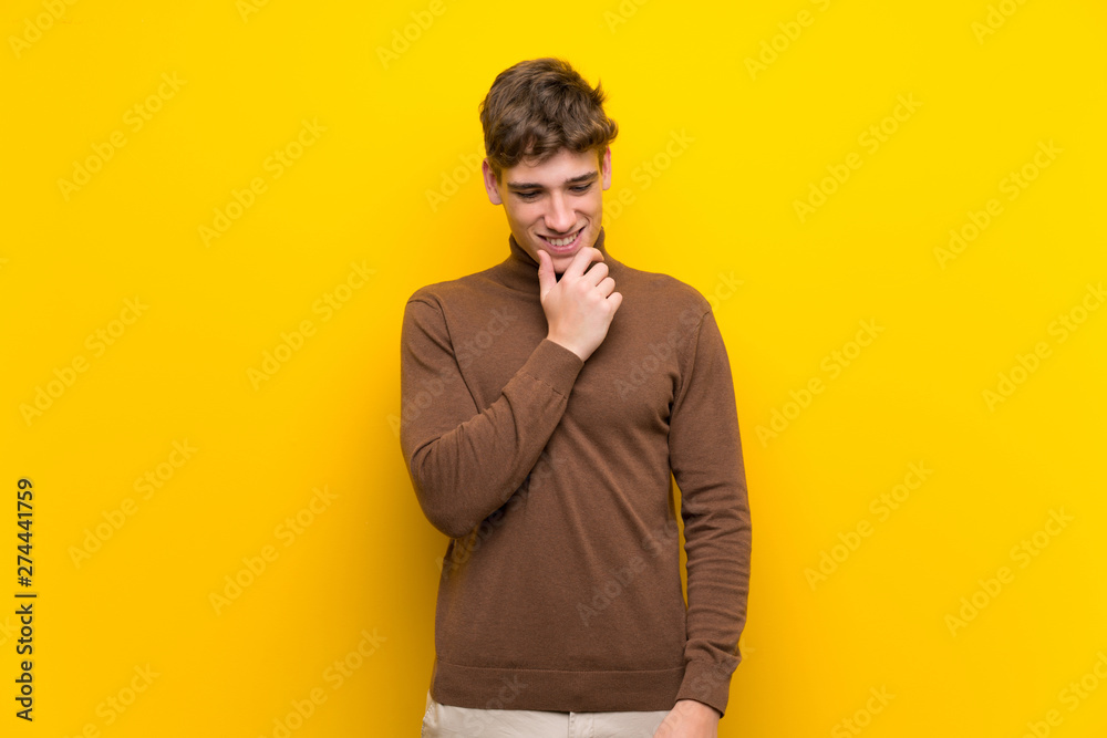 Obraz premium Handsome young man over isolated yellow background looking to the side
