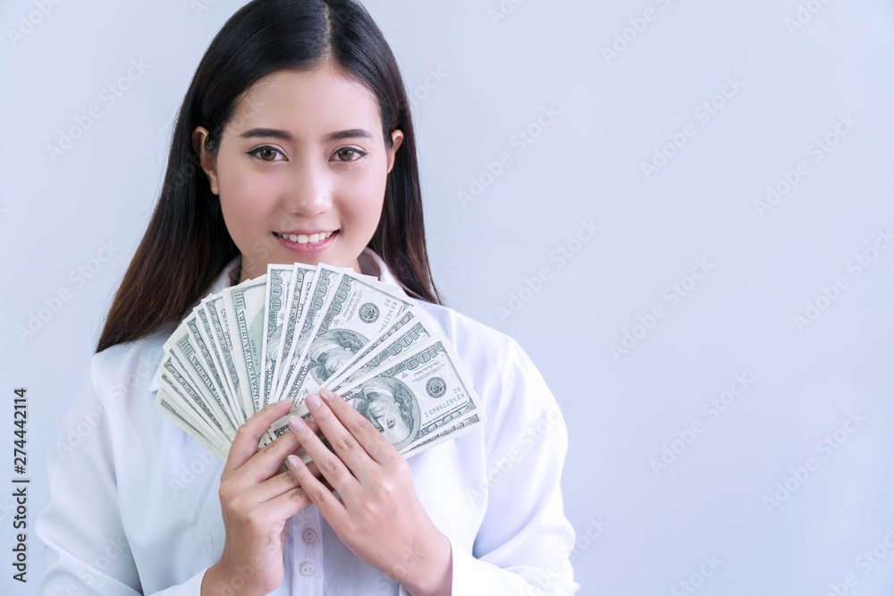Cheerful smiling young woman holding money dollars in her hand looking at camera on white background. Cheerful smiling young woman holding money dollars in her hand looking at camera on white background.
