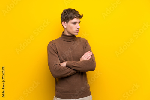 Handsome young man over isolated yellow background portrait
