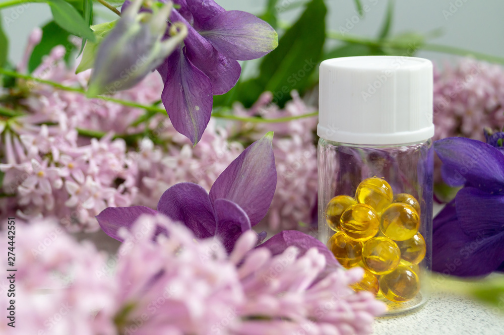 a jar with fish oil capsules and purple liliac flowers a jar with fish oil capsules and purple liliac flowers