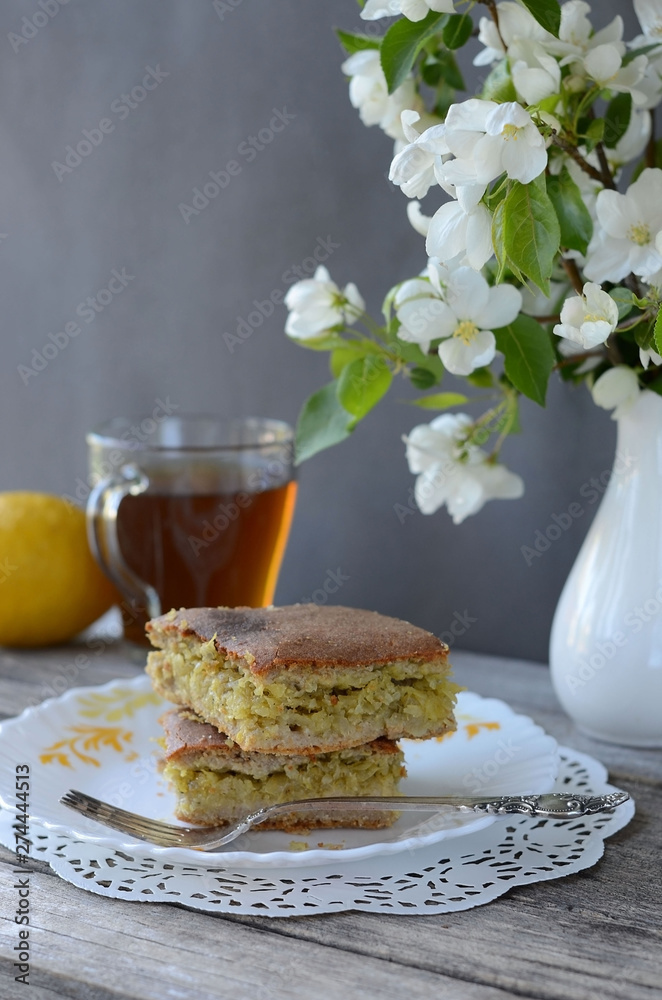 Pie with cabbage filling on a plate  with a vase of flowers. Bakery products